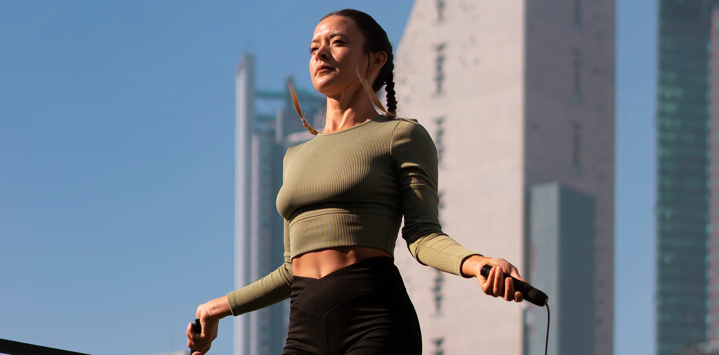 Woman skipping rope outdoors between city buildings